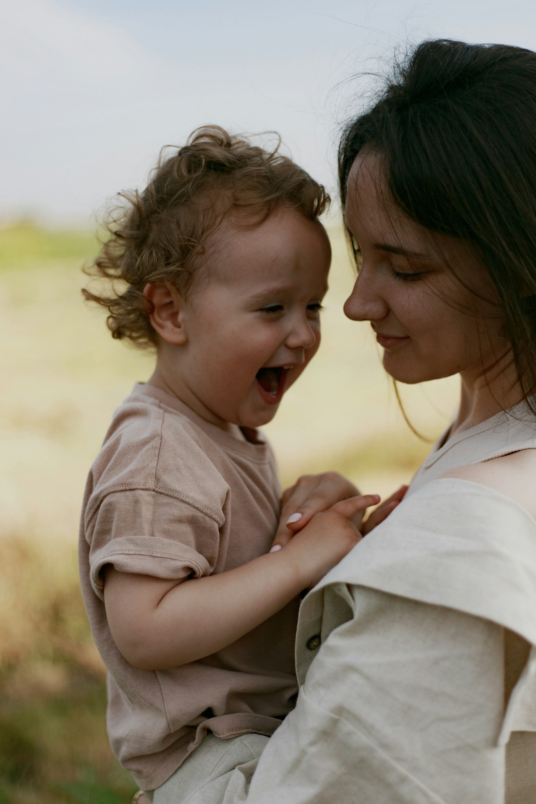 Mãe abraçando o filho pequeno ao ar livre, na luz do fim de tarde